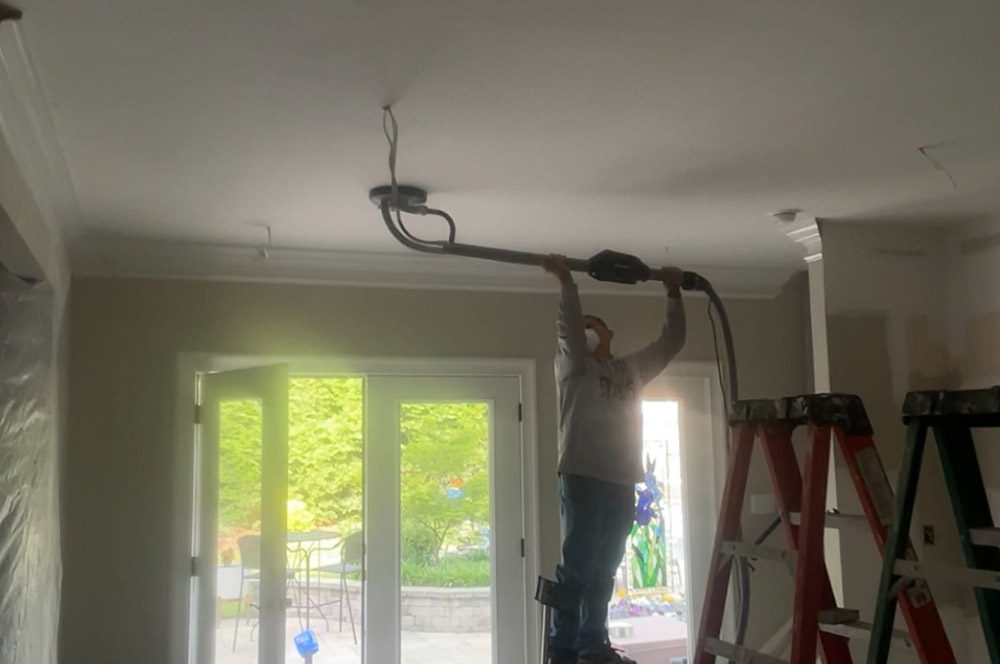 Technician vacuum power sanding on stilts